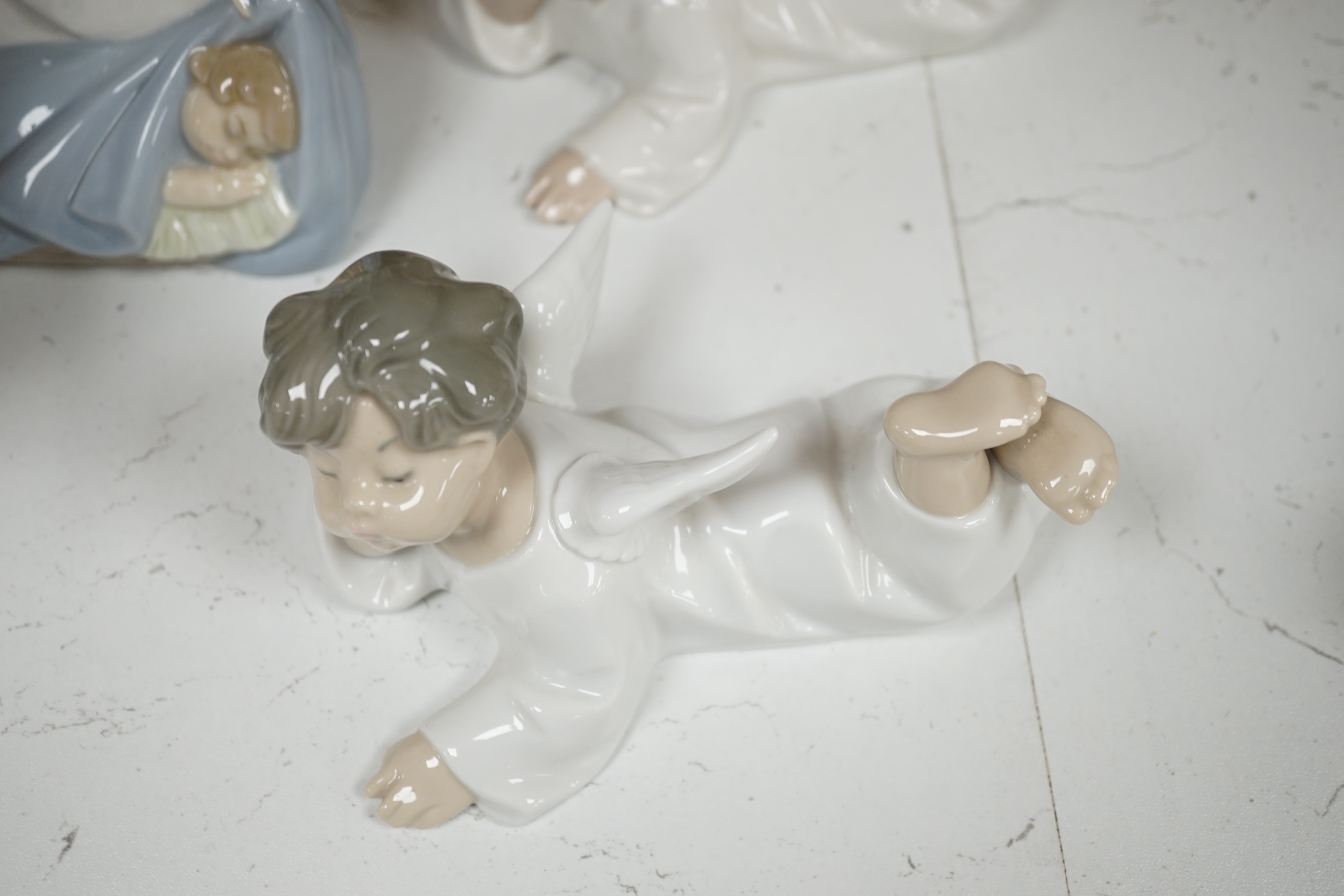 A large Lladro figure of children in a pram, seven models of angels and a boy with a dog (9)